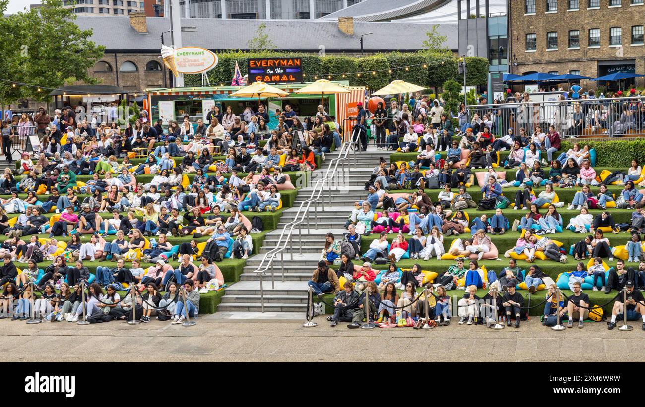Londra, Regno Unito. 25 luglio 2024. Le persone guardano il cinema all'aperto gratuito all'Everyman on the Canal, un grande schermo installato a Granary Square Steps, King's Cross, nonostante il clima umido e mutevole di oggi, e sembrano godersi la loro estate con l'intrattenimento della città. Everyman on the Canal proietta 4 film al giorno tra il 1° luglio e il 18 agosto. Crediti: Imageplotter/Alamy Live News Foto Stock