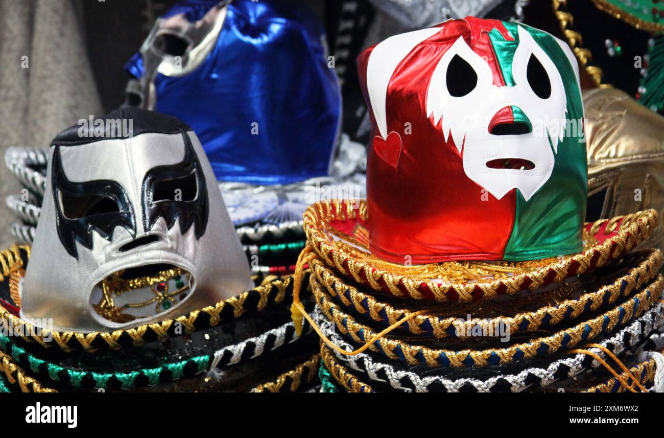 Foto ravvicinata di maschere da wrestling sedute in pile di cappelli messicani "sombreros" Foto Stock