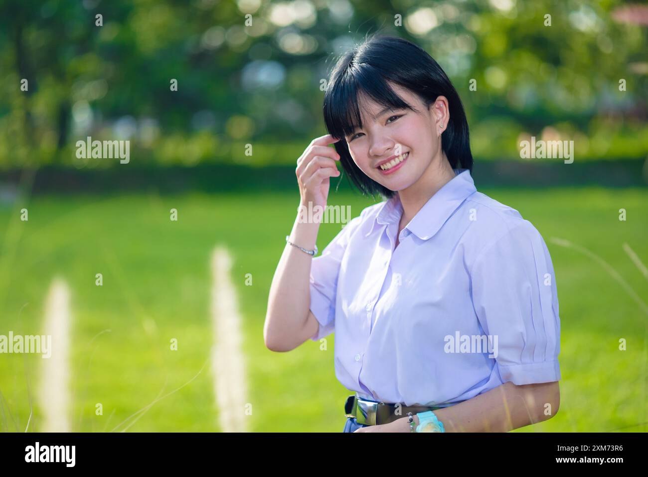 Ritratto sorriso felice adolescente scuola asiatica in uniforme al parco verde all'aperto con spazio per fotocopie Foto Stock