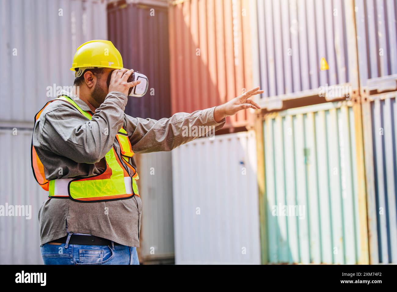 I lavoratori che utilizzano dispositivi con cuffie e auricolari VR Vision Pro Technology lavorano presso Container Yard Construction Site innovazione nel settore della logistica Foto Stock