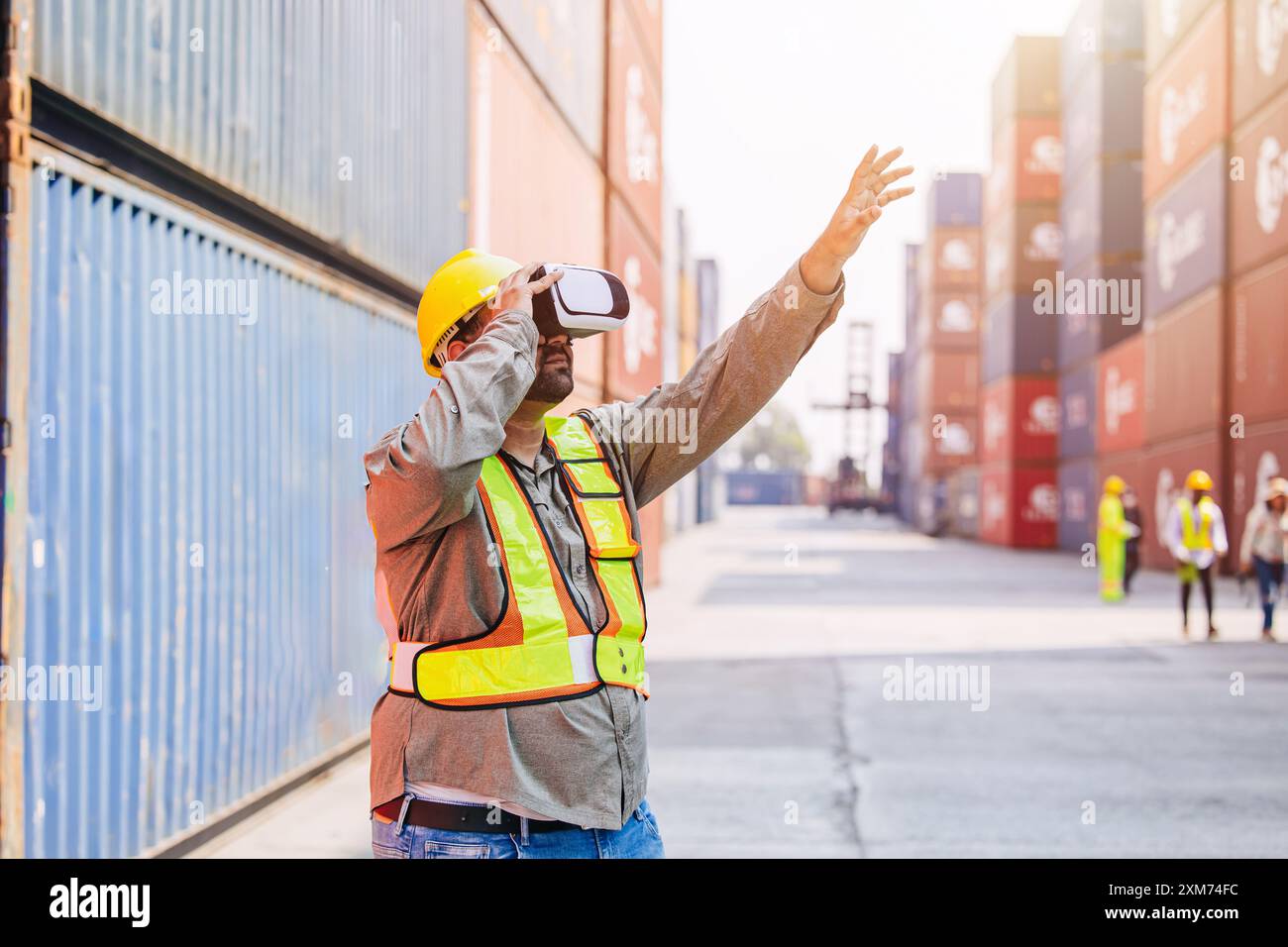 I lavoratori che utilizzano dispositivi con cuffie e auricolari VR Vision Pro Technology lavorano presso Container Yard Construction Site innovazione nel settore della logistica Foto Stock