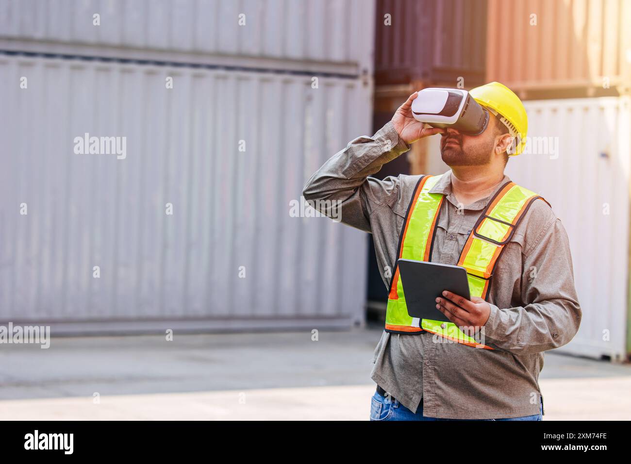 I lavoratori che utilizzano dispositivi con cuffie e auricolari VR Vision Pro Technology lavorano presso Container Yard Construction Site innovazione nel settore della logistica Foto Stock