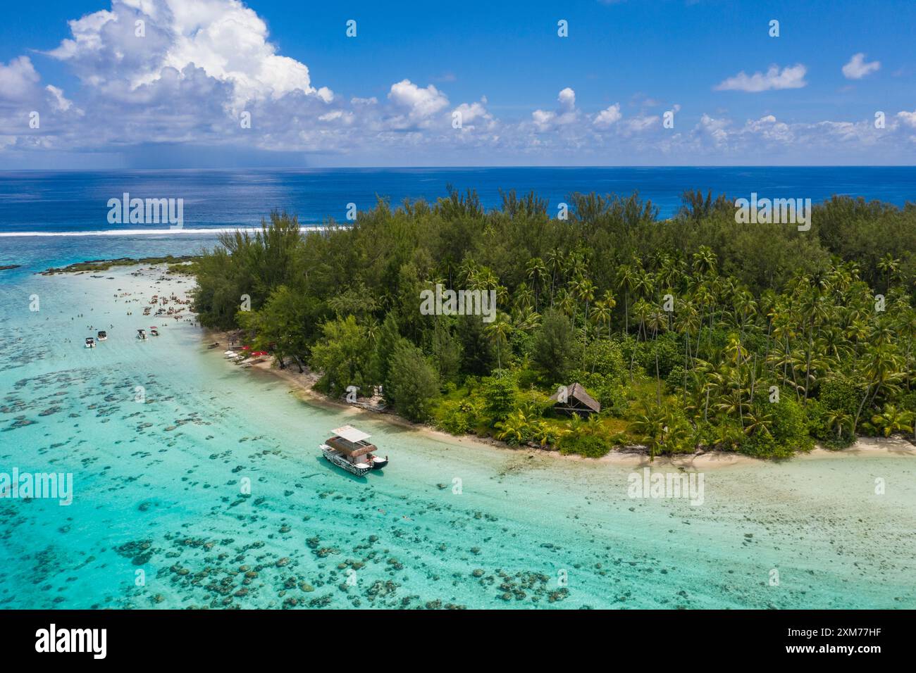Veduta aerea della barca del tour e della gente che si rilassa e ascolta musica dal vivo seduto ai tavoli da picnic nella laguna, a Moorea, nelle isole Windward, nel po francese Foto Stock
