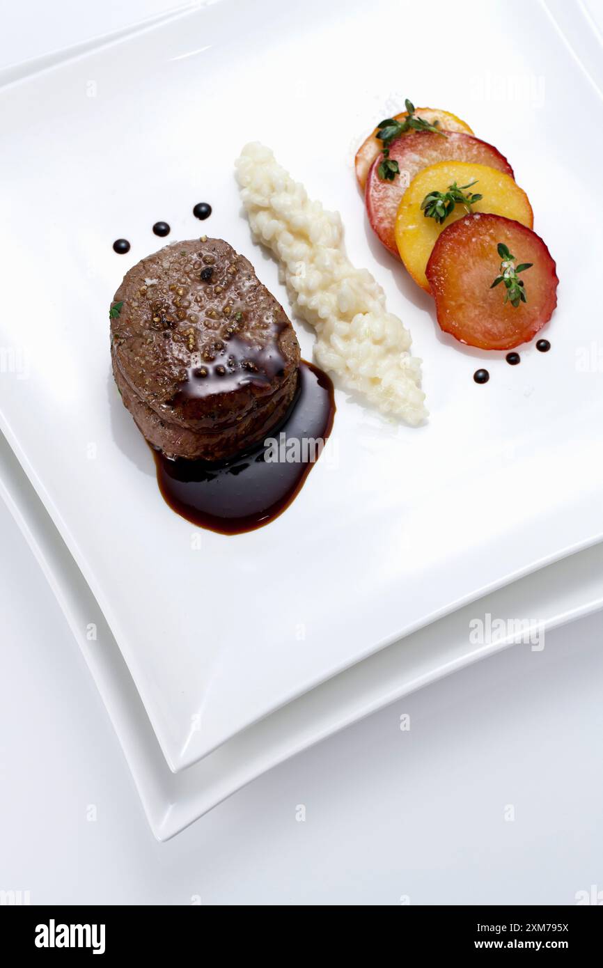 Tournedos di filetto di manzo con risotto e pesche da vigna Foto Stock