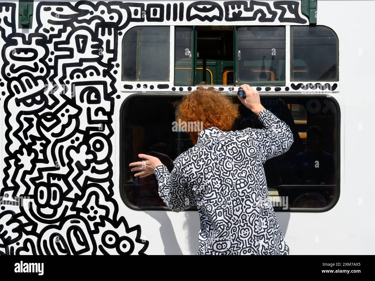 Tenterden, Kent, Regno Unito. 26 luglio 2024. L'artista di fama internazionale Mr Doodle (Sam Cox) crea il primo Doodle Train al mondo, che copre una carrozza ferroviaria di 64 piedi con i suoi doodles caratteristici, per celebrare il 50 ° anniversario della ferrovia Kent e East Sussex, alla sua base alla stazione di Tenterden nella sua città natale. Crediti: Phil Robinson/Alamy Live News Foto Stock