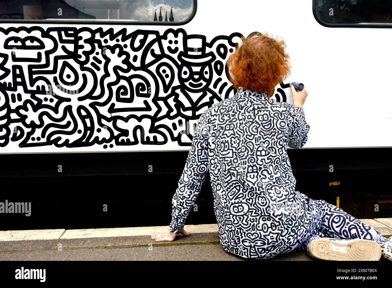 Tenterden, Kent, Regno Unito. 26 luglio 2024. L'artista di fama internazionale Mr Doodle (Sam Cox) crea il primo Doodle Train al mondo, che copre una carrozza ferroviaria di 64 piedi con i suoi doodles caratteristici, per celebrare il 50 ° anniversario della ferrovia Kent e East Sussex, alla sua base alla stazione di Tenterden nella sua città natale. Crediti: Phil Robinson/Alamy Live News Foto Stock