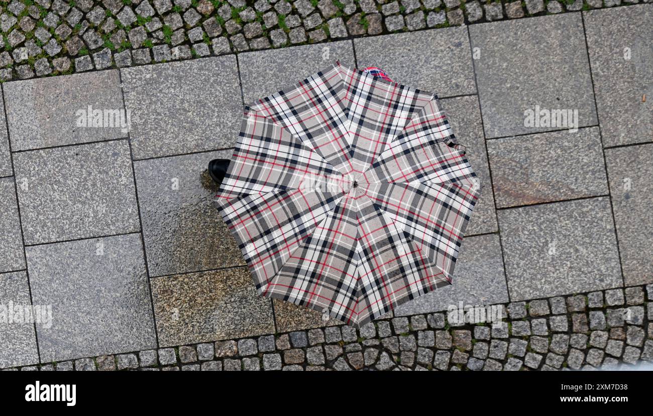 Erfurt, Germania. 26 luglio 2024. Un uomo con un ombrello cammina lungo Johannesstraße nella città vecchia di Erfurt. L'inizio del weekend sarà scomodo bagnato e grigio. Il servizio meteorologico tedesco (DWD) avverte di forti temporali, forti precipitazioni fino a 50 litri per metro quadrato e grandine per la Turingia nei prossimi giorni. Crediti: Martin Schutt/dpa/Alamy Live News Foto Stock