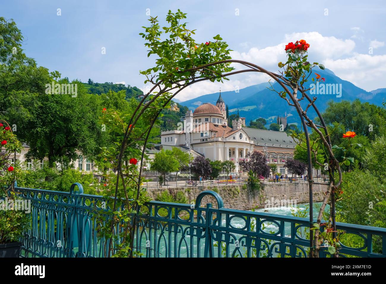 Merano, alto Adige, Italia - Kurhaus sul fiume Passer, sul lungomare di Passer nel centro storico. Davanti, rose rosse sul ponte termale. Foto Stock