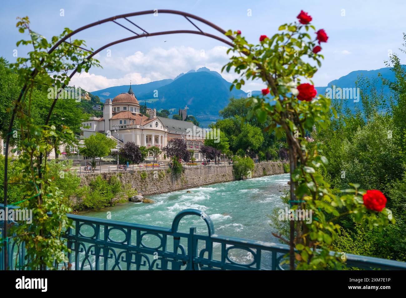 Merano, alto Adige, Italia - Kurhaus sul fiume Passer, sul lungomare di Passer nel centro storico. Davanti, rose rosse sul ponte termale. Foto Stock