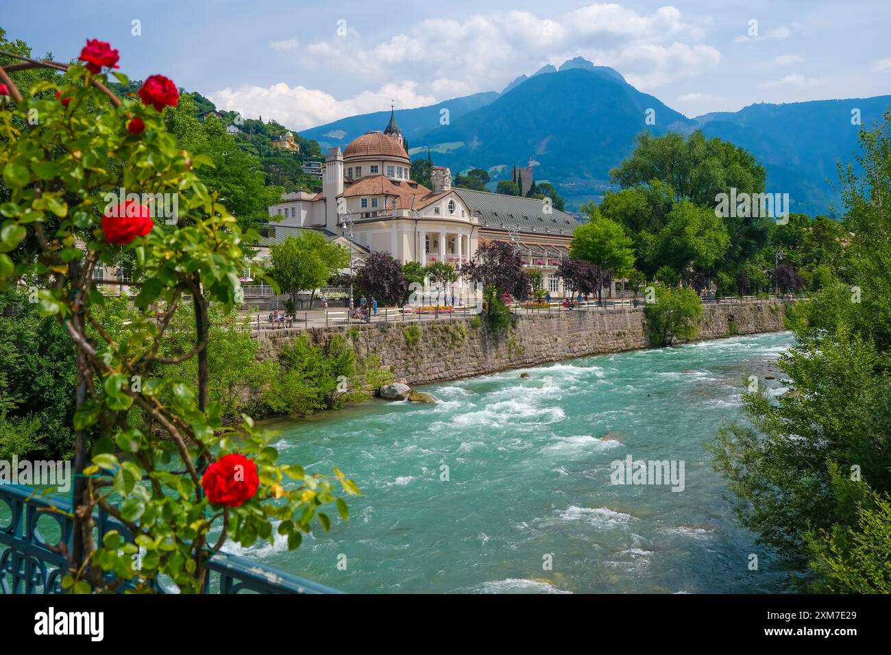 Merano, alto Adige, Italia - Kurhaus sul fiume Passer, sul lungomare di Passer nel centro storico. Davanti, rose rosse sul ponte termale. Foto Stock