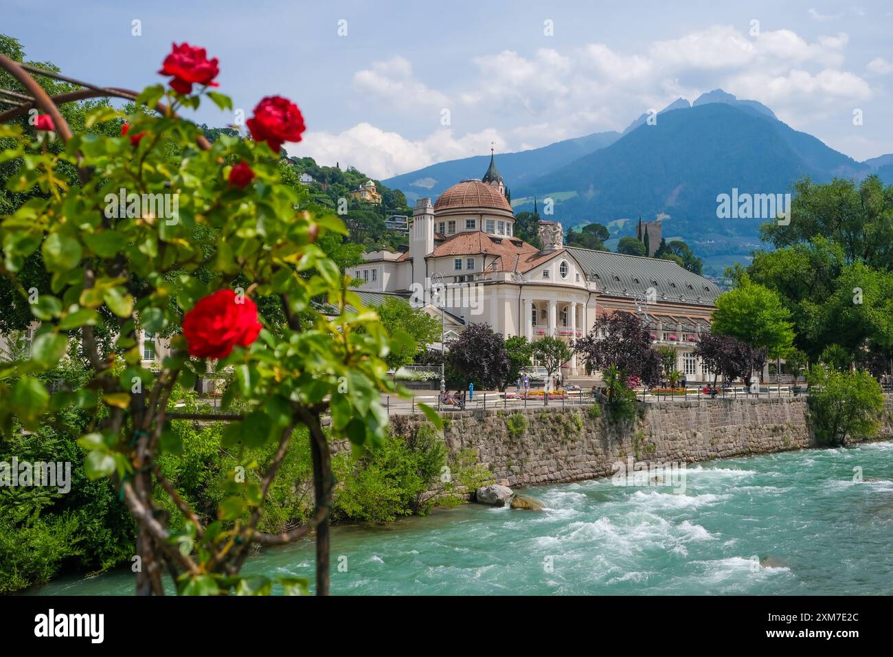 Merano, alto Adige, Italia - Kurhaus sul fiume Passer, sul lungomare di Passer nel centro storico. Davanti, rose rosse sul ponte termale. Foto Stock