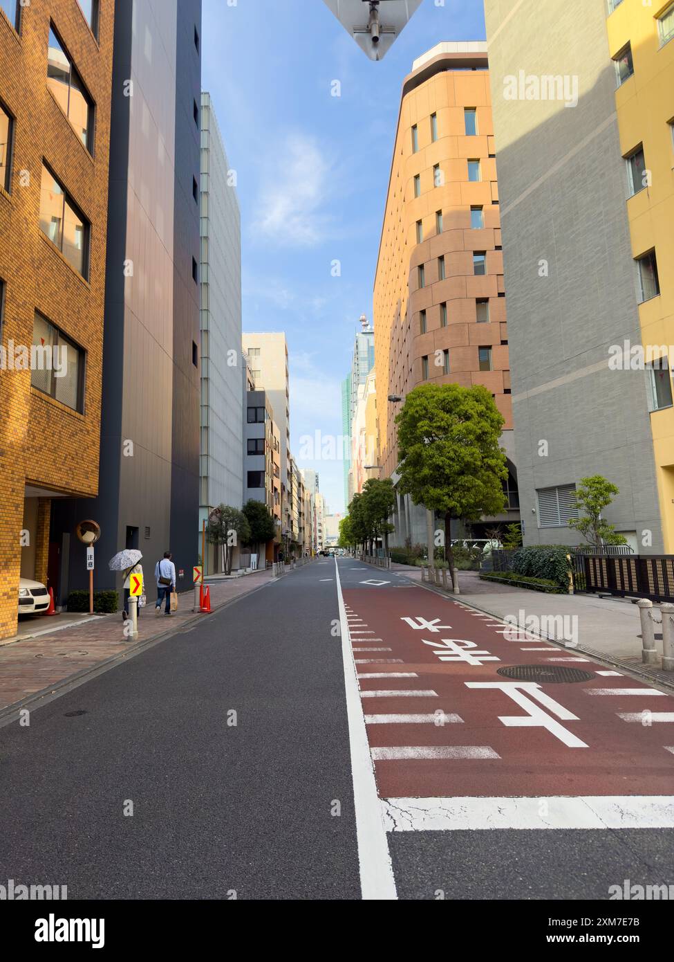 Alti edifici della città di Tokyo e strade vuote contro il cielo nuvoloso blu, Giappone Foto Stock