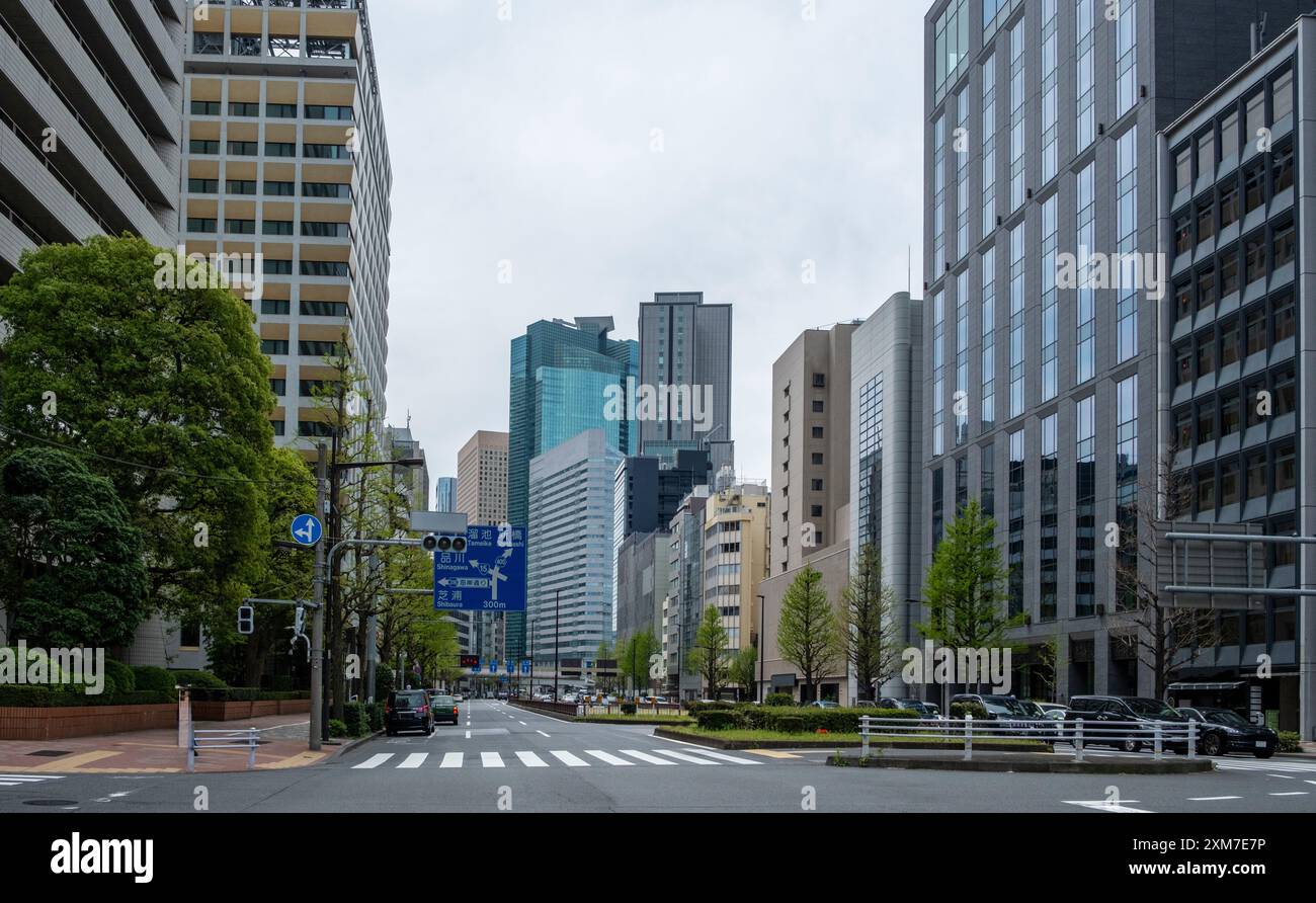 Alti edifici della città di Tokyo semafori e cartelli stradali contro il cielo nuvoloso, Giappone Foto Stock