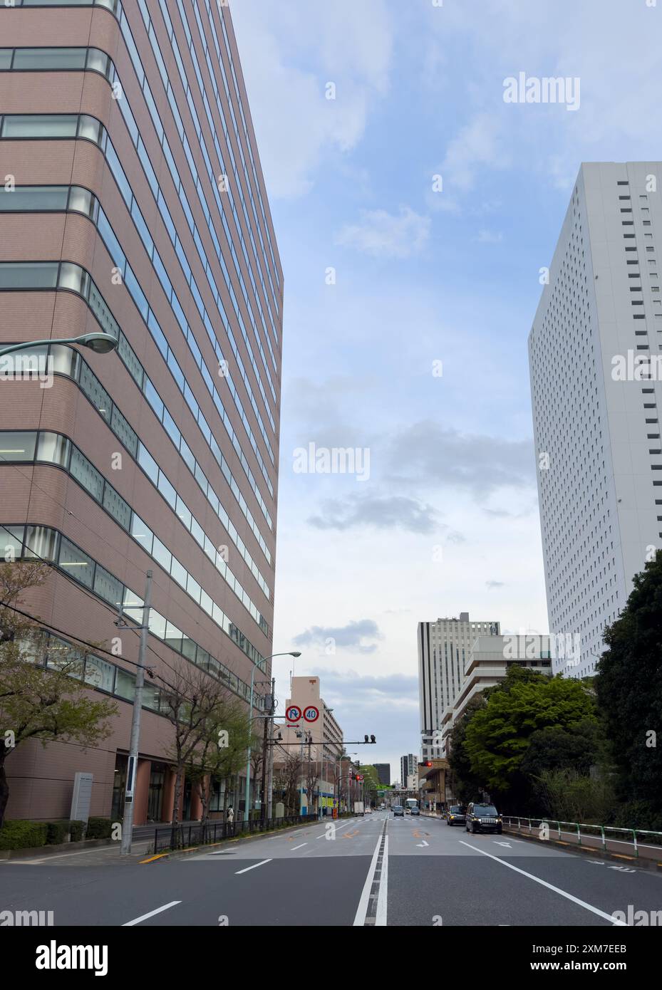 Alti edifici della città di Tokyo e strade vuote contro il cielo nuvoloso blu, Giappone Foto Stock