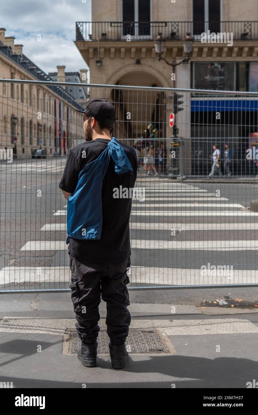 Un uomo sta dietro una griglia metallica che è stata installata per motivi di sicurezza prima dell'inizio dei Giochi Olimpici. Parigi, Francia, 22 luglio 2024 Foto Stock