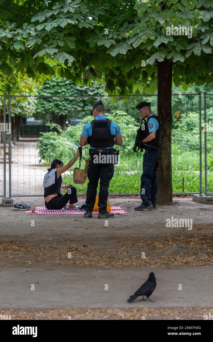 La polizia chiede a una donna di lasciare il suo posto da picnic nei giardini delle Tuileries a causa delle misure di sicurezza per le Olimpiadi. Parigi, Francia, 22 luglio 2024 Foto Stock