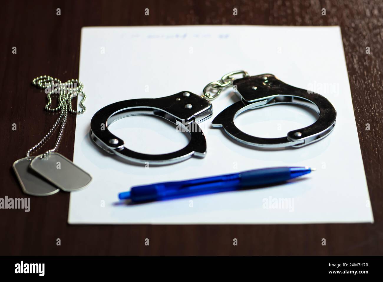 Manette e un distintivo militare su carta bianca, con una penna blu nelle vicinanze Foto Stock