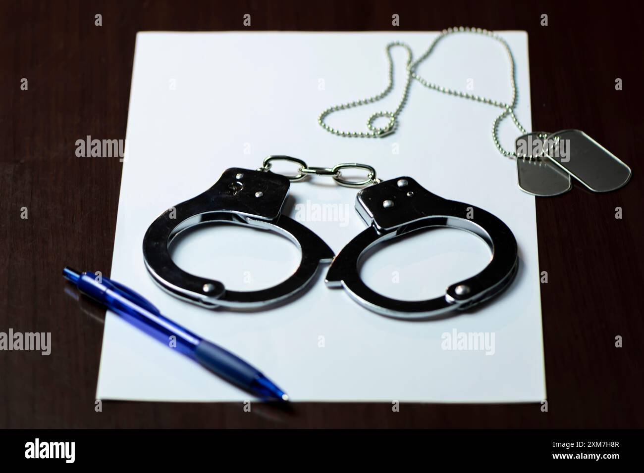 Manette e un distintivo militare su carta bianca, con una penna blu nelle vicinanze Foto Stock