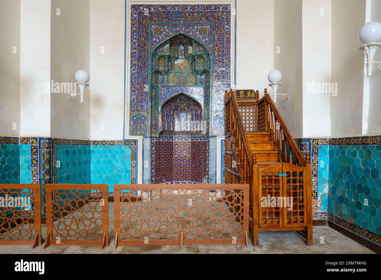 Interno di una moschea storica con colorate piastrelle islamiche, minbar in legno e mihrab ornato all'interno della moschea Kalan a Bukhara, Uzbekistan Foto Stock