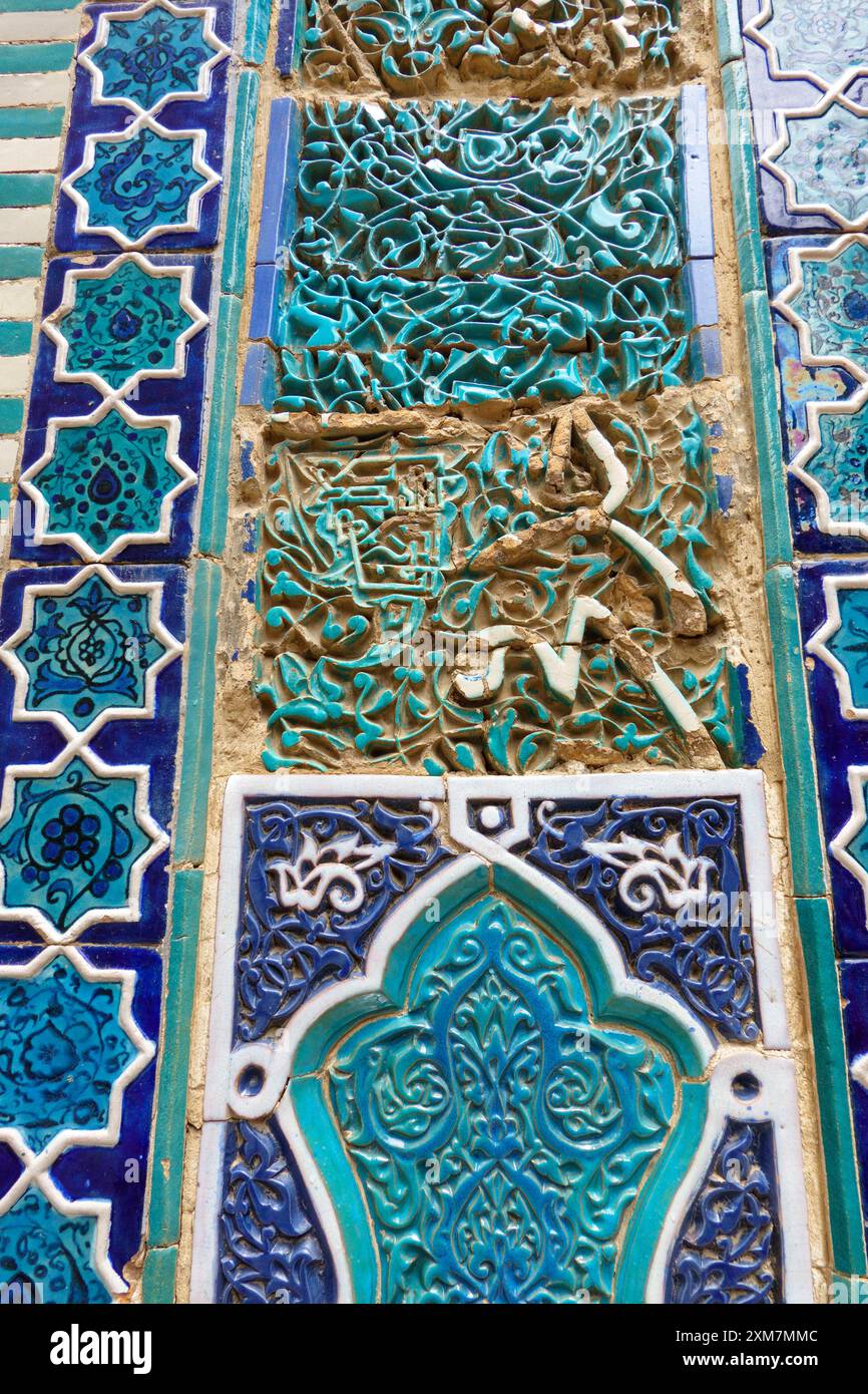 Intricati motivi geometrici e floreali islamici di piastrelle in blu e turchese con invecchiamento ed erosione visibili su un antico muro a Samarcanda, Uzbekistan Foto Stock