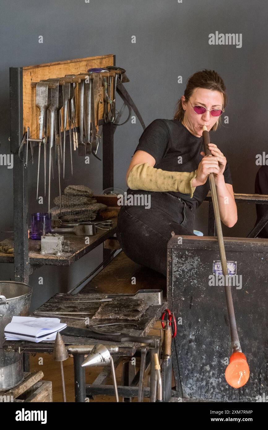 Axelle Mary, artista e soffiatrice di vetro francese, al lavoro soffiando vetro nel suo studio in Galles, Regno Unito Foto Stock