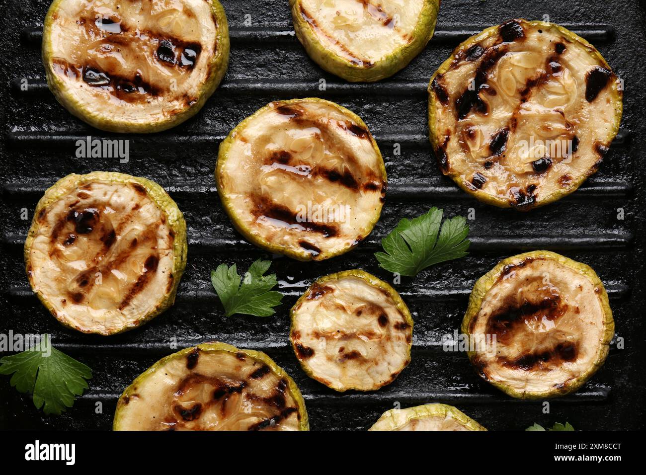 Gustose fette di zucchine grigliate con prezzemolo sulla padella, piatto Foto Stock