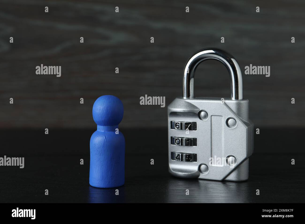 Figura umana blu e lucchetto di metallo sul tavolo di legno nero, primo piano Foto Stock