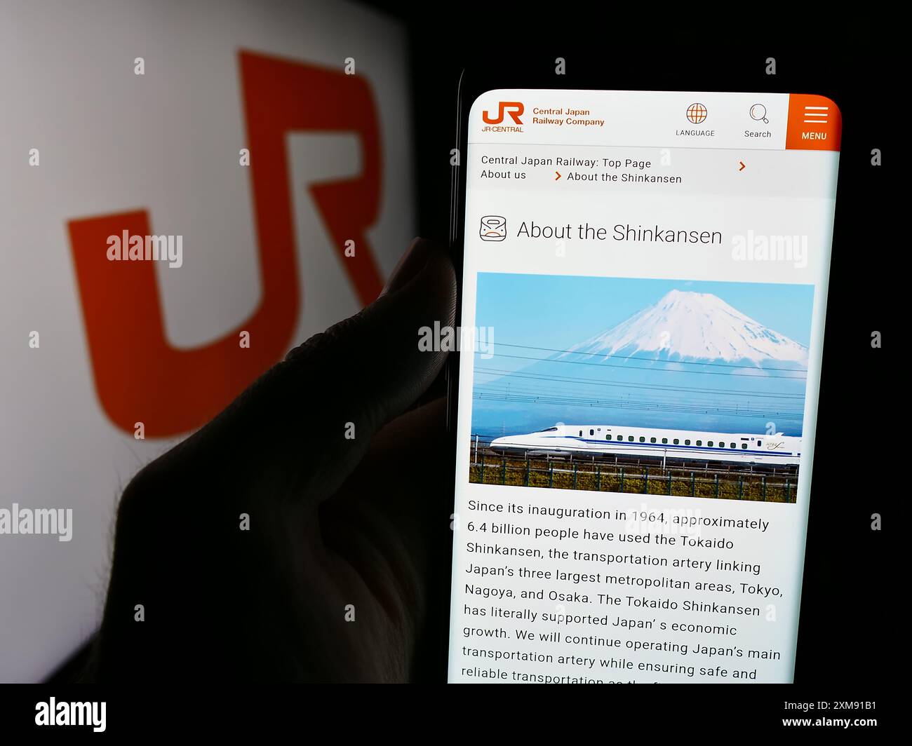 Persona che detiene un cellulare con pagina web dell'azienda ferroviaria giapponese Central Japan Railway Company con logo. Messa a fuoco al centro del display del telefono. Foto Stock