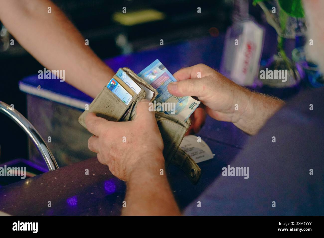 Parma, Italia 24 luglio 2024 Un cliente paga il barman in un bar con una banconota da dieci euro. Simboleggiando il flusso di denaro nel commercio quotidiano. Il Foto Stock