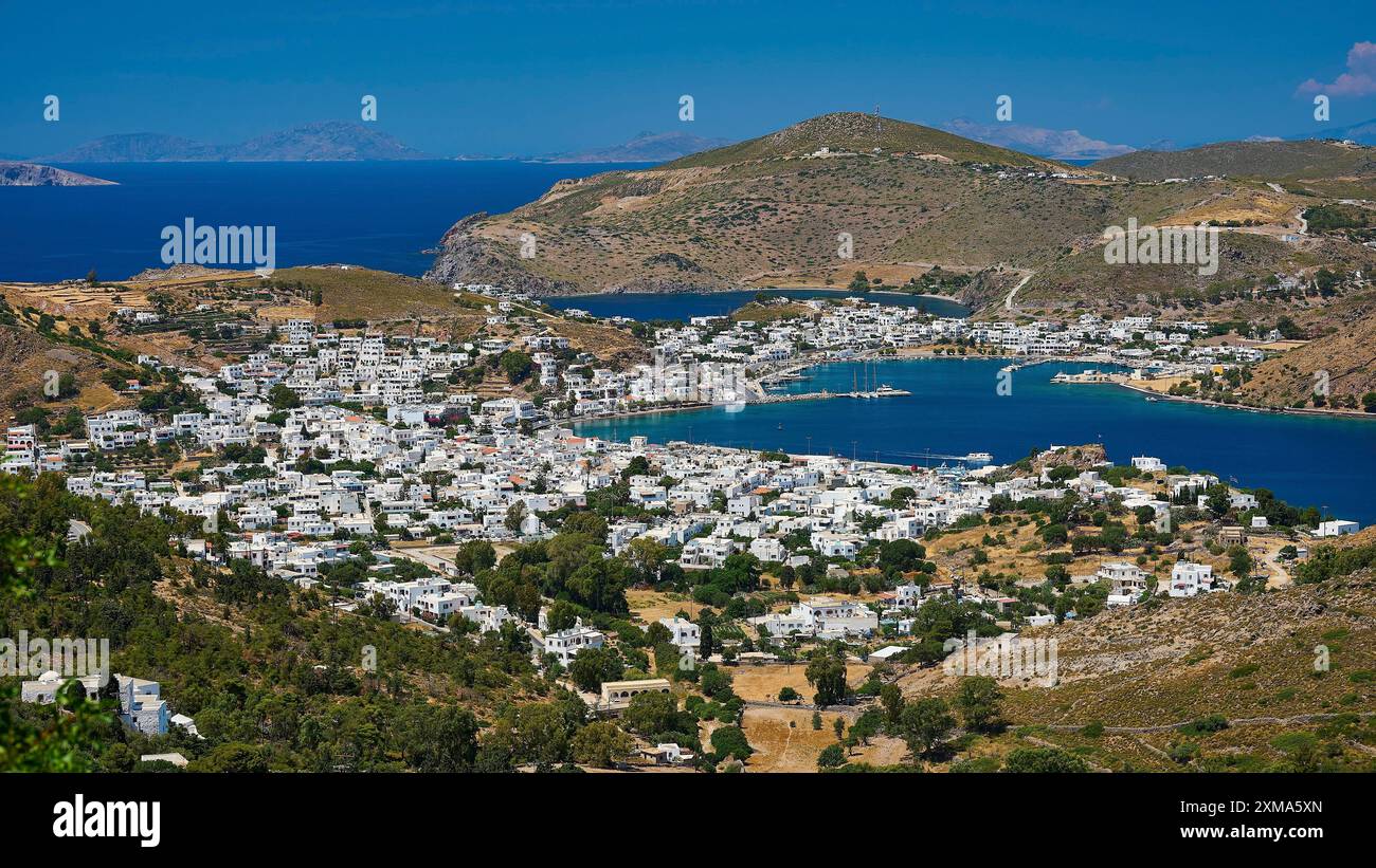 Pittoresca cittadina costiera con case bianche e montagne sullo sfondo, circondata dal mare blu in clima mediterraneo, Skala e Patmos Foto Stock