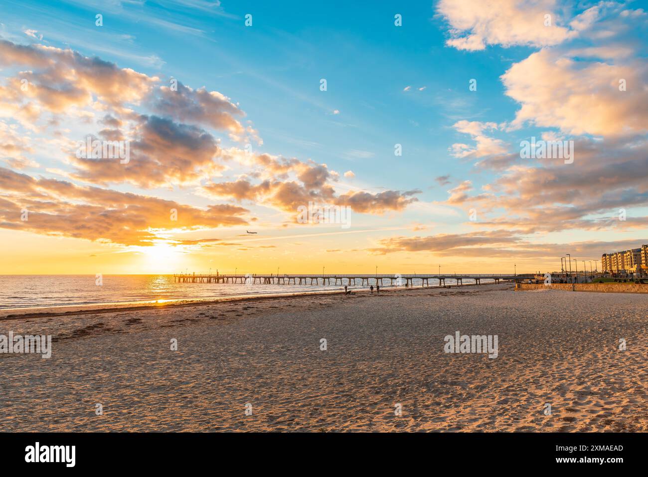 Glenelg Beach con molo e persone che camminano lungo la riva durante il tramonto, Australia meridionale Foto Stock