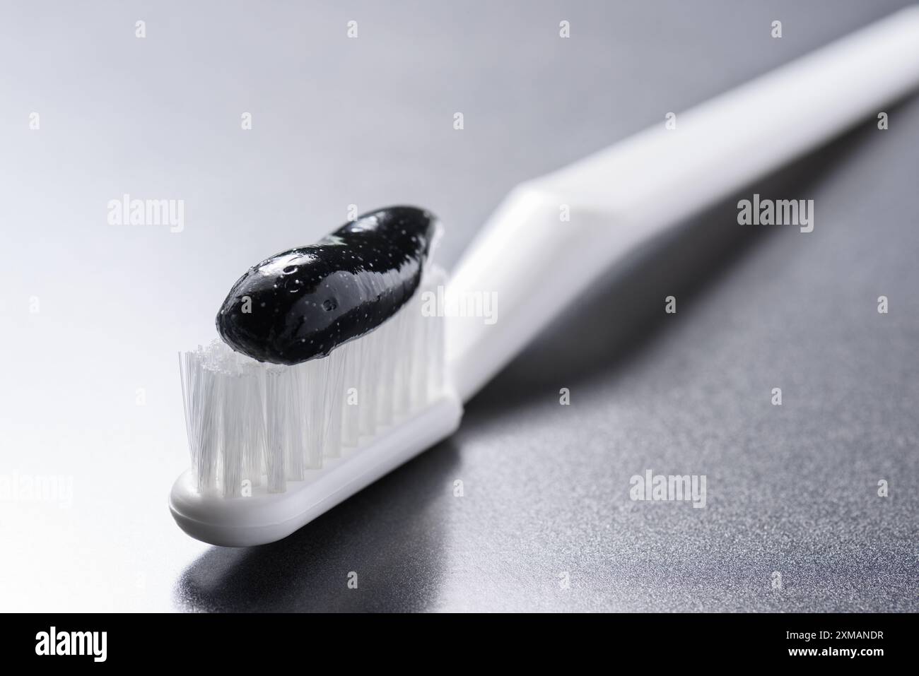 Vista ravvicinata del dentifricio nero al carbone su uno spazzolino da denti Foto Stock