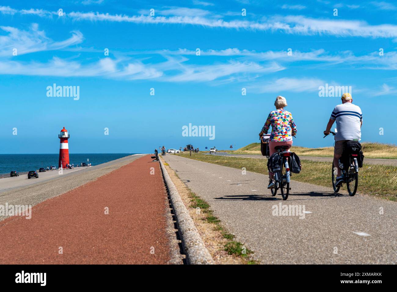 Diga del Mare del Nord vicino a Westkapelle, faro di Westkapelle Laag, ciclisti sulla pista ciclabile Zeeuwse Wind Route, provincia della Zelanda, Walcheren Foto Stock
