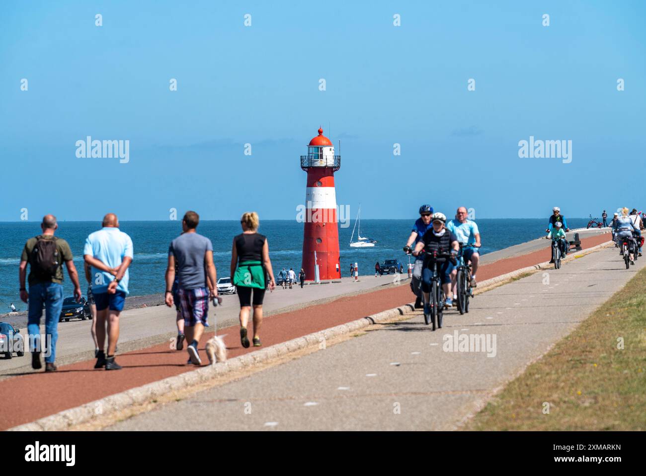 Diga del Mare del Nord vicino a Westkapelle, faro di Westkapelle Laag, ciclisti sulla pista ciclabile Zeeuwse Wind Route, provincia della Zelanda, Walcheren Foto Stock