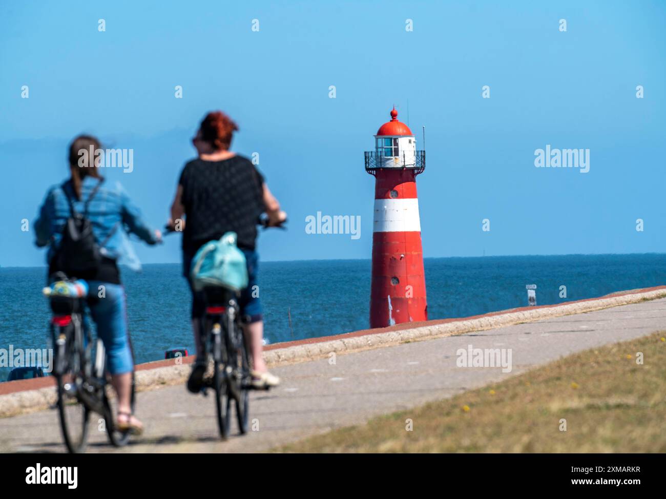 Diga del Mare del Nord vicino a Westkapelle, faro di Westkapelle Laag, ciclisti sulla pista ciclabile Zeeuwse Wind Route, provincia della Zelanda, Walcheren Foto Stock