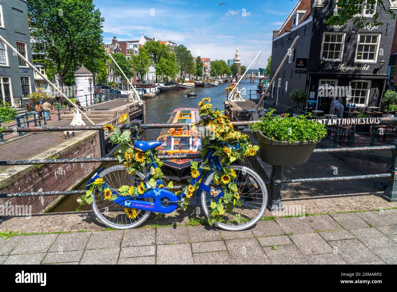 Sint Antoniesluis, sul canale Oudeschans, bicicletta decorata con girasoli, barca da crociera sul canale, caffetteria, De Sluyswacht, Amsterdam, paesi Bassi Foto Stock