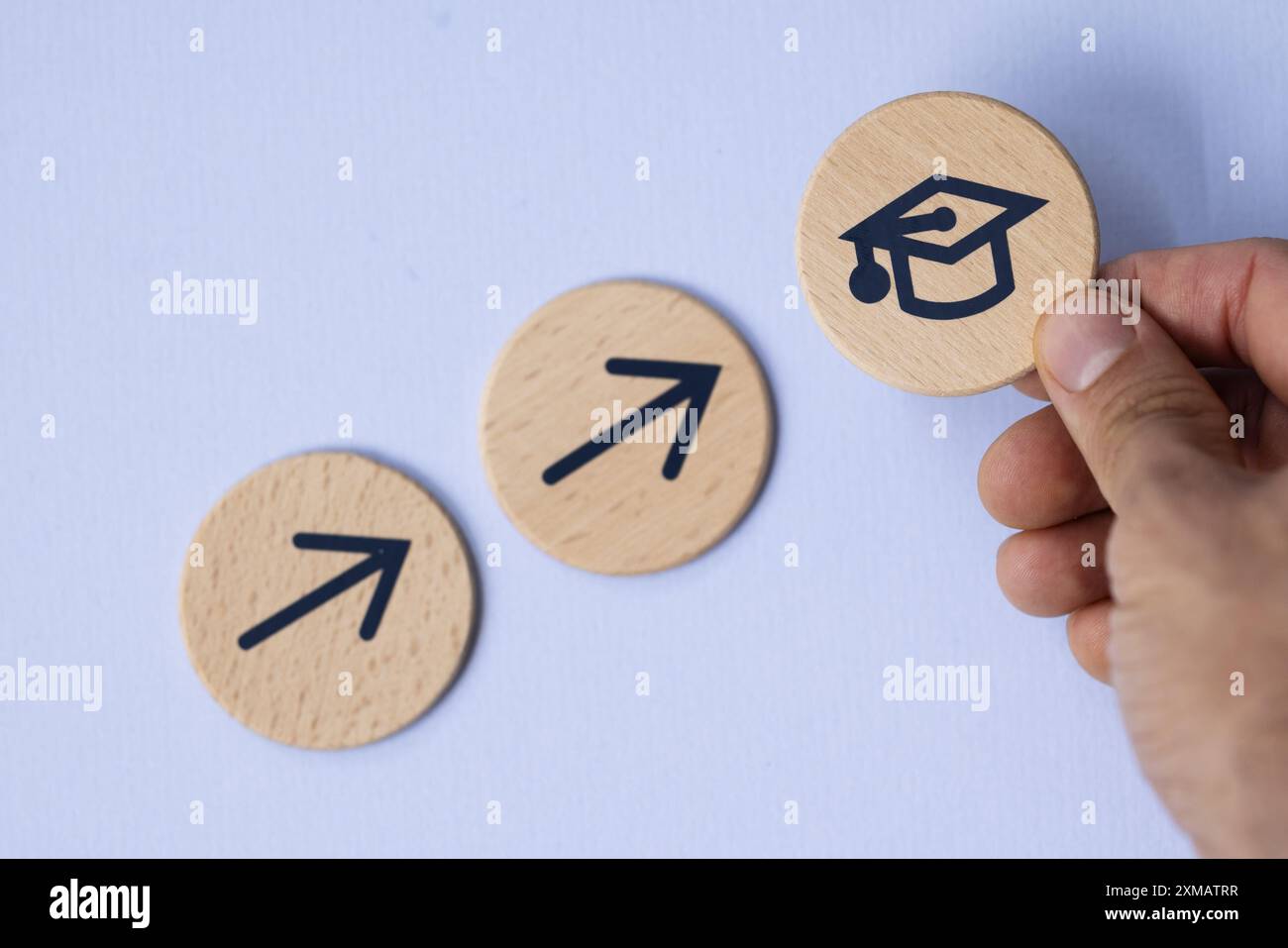 Mano di un uomo con diploma blu su scala in legno che simboleggia il successo accademico e la crescita della carriera nel concetto di laurea universitaria. Foto Stock
