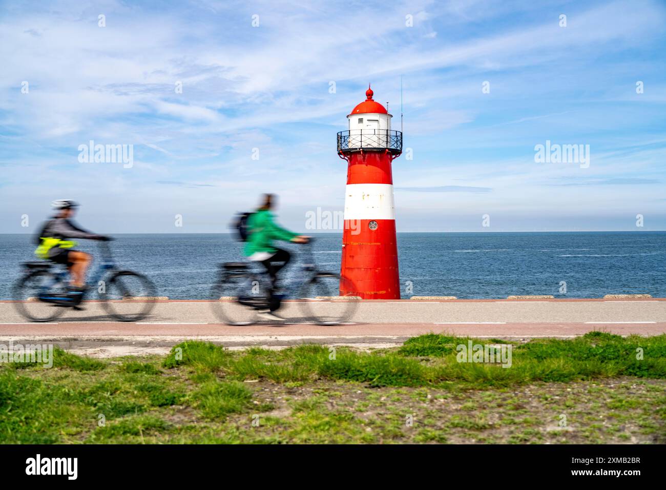 Diga del Mare del Nord vicino a Westkapelle, faro di Westkapelle Laag, ciclisti sulla pista ciclabile Zeeuwse Wind Route, provincia della Zelanda, Walcheren Foto Stock