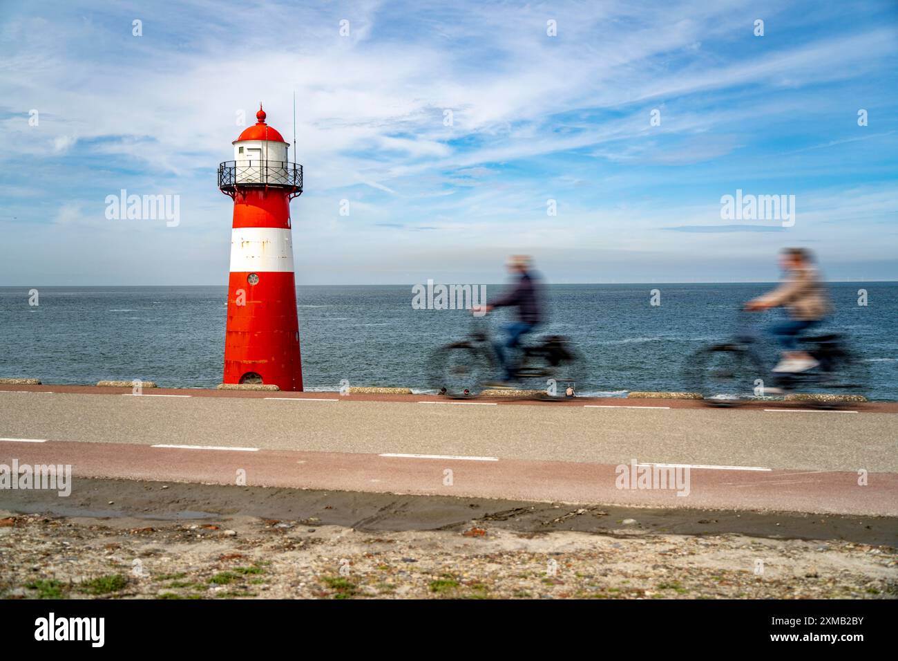 Diga del Mare del Nord vicino a Westkapelle, faro di Westkapelle Laag, ciclisti sulla pista ciclabile Zeeuwse Wind Route, provincia della Zelanda, Walcheren Foto Stock