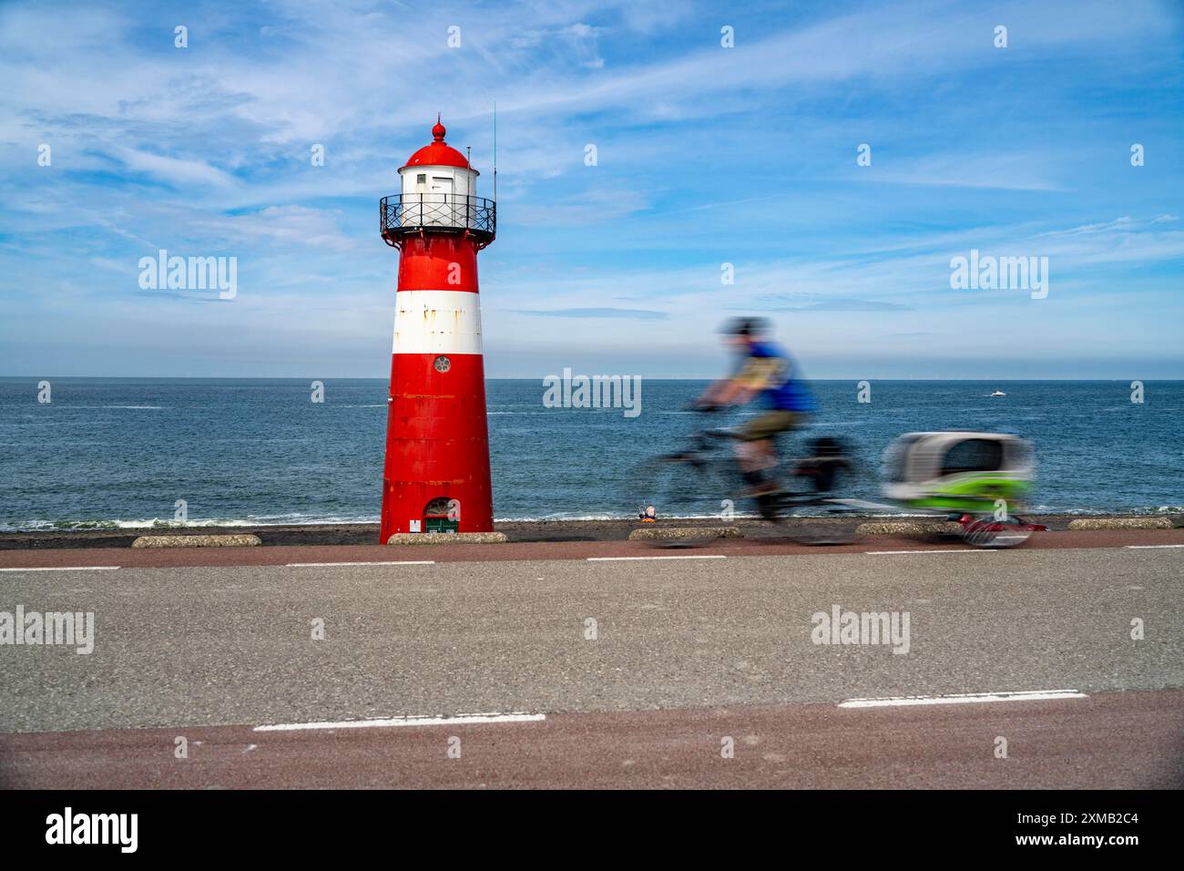 Diga del Mare del Nord vicino a Westkapelle, faro di Westkapelle Laag, ciclisti sulla pista ciclabile Zeeuwse Wind Route, rimorchio per cani, provincia della Zelanda Foto Stock