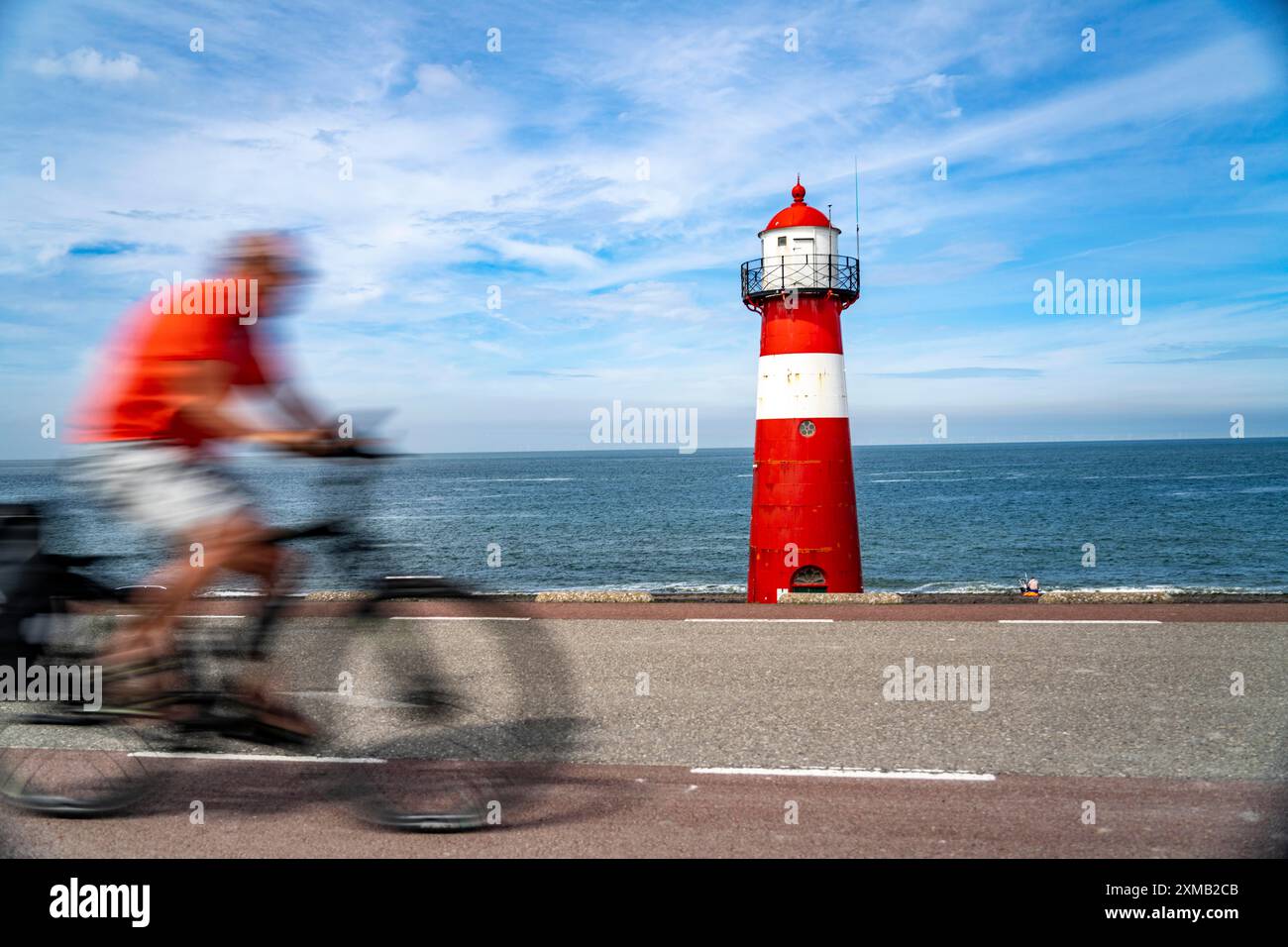 Diga del Mare del Nord vicino a Westkapelle, faro di Westkapelle Laag, ciclisti sulla pista ciclabile Zeeuwse Wind Route, provincia della Zelanda, Walcheren Foto Stock