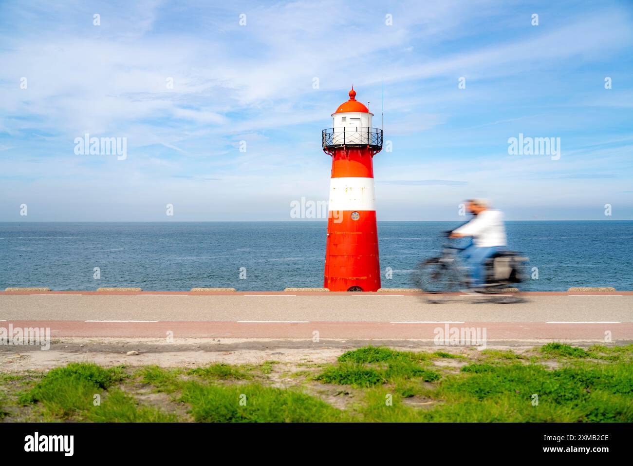Diga del Mare del Nord vicino a Westkapelle, faro di Westkapelle Laag, ciclisti sulla pista ciclabile Zeeuwse Wind Route, provincia della Zelanda, Walcheren Foto Stock