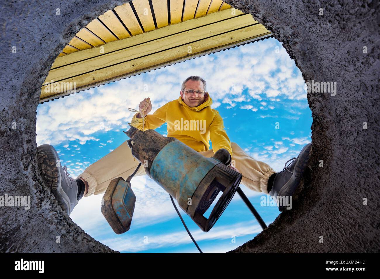Pompaggio del serbatoio settico, vista dal basso dell'operatore che installa la pompa sommersa per acque reflue nell'anello del pozzetto di calcestruzzo. Foto Stock