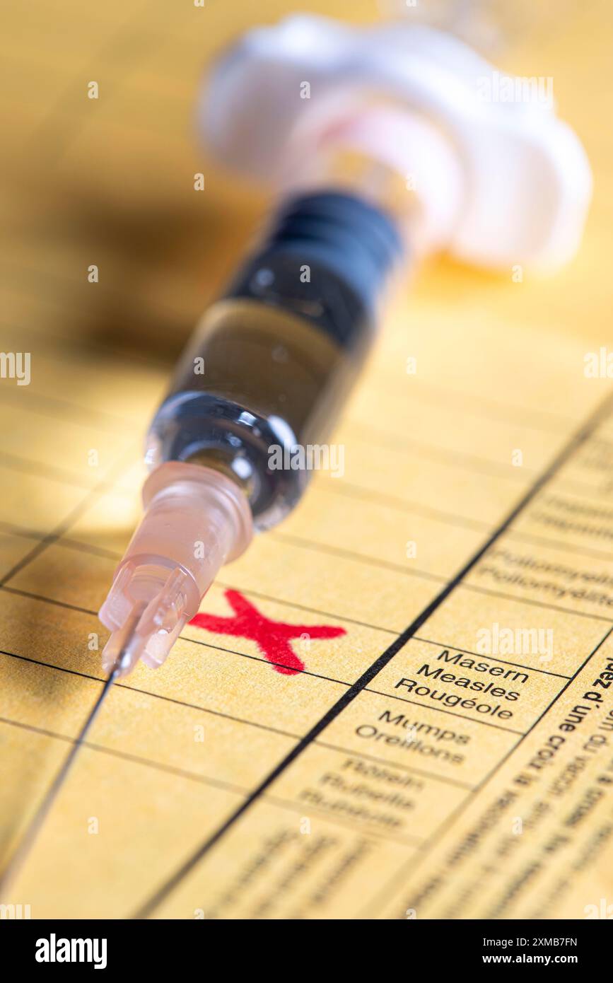 Foto simbolica vaccinazione contro il morbillo, certificato di vaccinazione, siringa con vaccino contro il morbillo Foto Stock