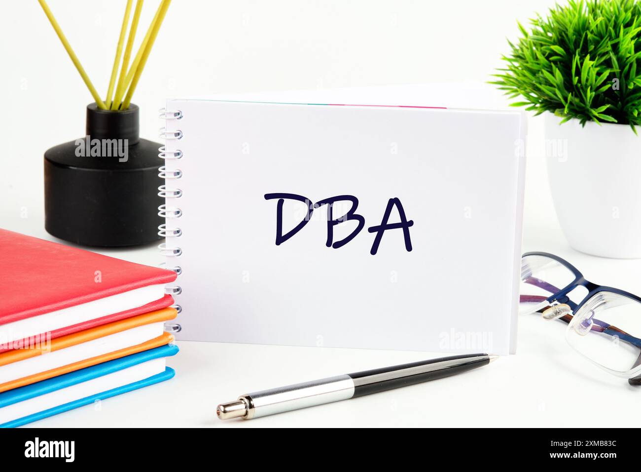 Termine aziendale. Business phrase DBA in un notebook su uno sfondo chiaro in una composizione con accessori business Foto Stock