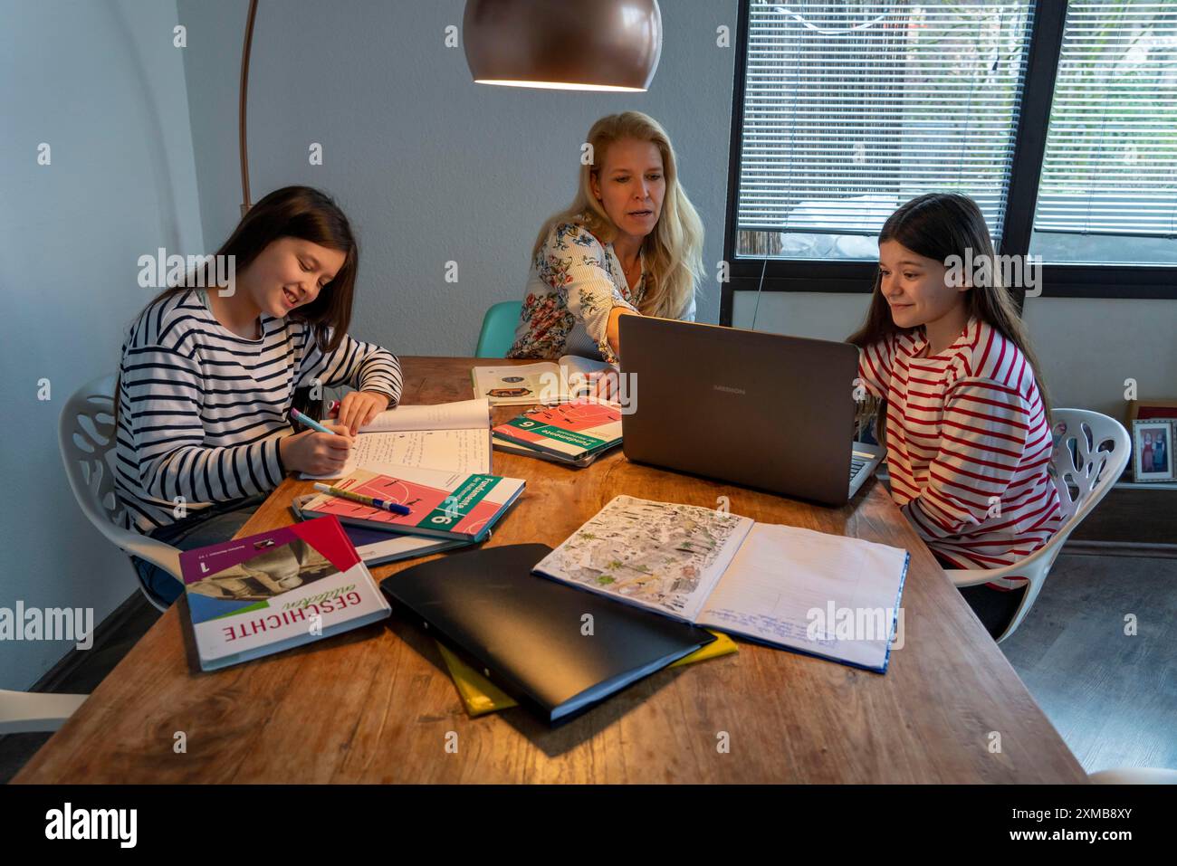 Homeschooling, durante il blocco nel gennaio 2021, la madre aiuta le sue due figlie, a casa, a imparare, con libri di testo e computer, chiusure scolastiche Foto Stock