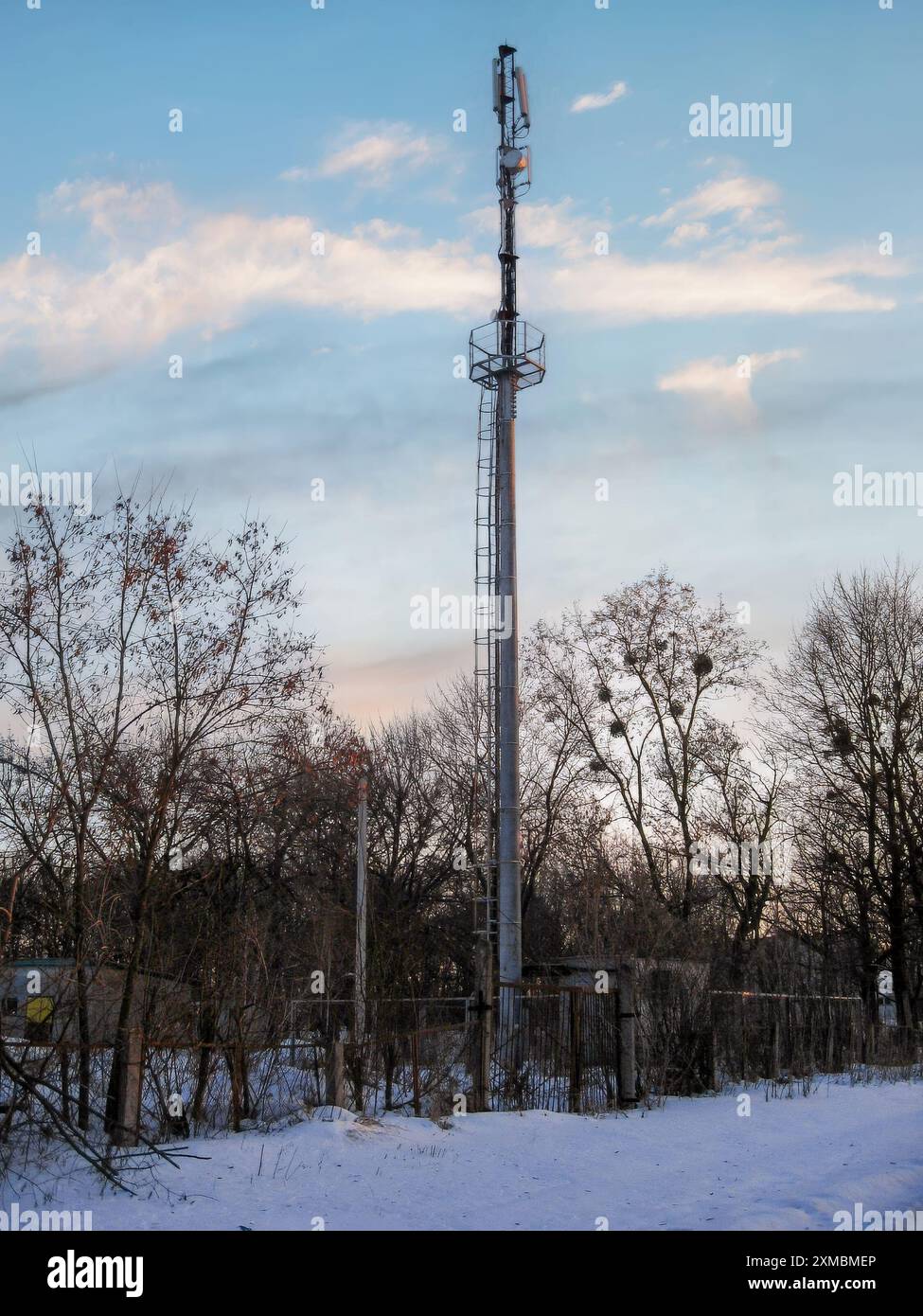 La torre delle telecomunicazioni in acciaio si erge su un paesaggio invernale con un cielo limpido. Foto Stock