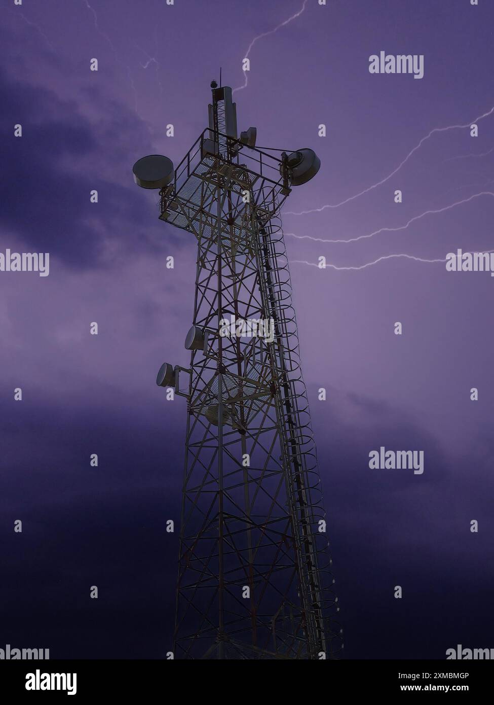 Una torre di comunicazione sotto un cielo buio e tempestoso con fulmini visibili. Foto Stock