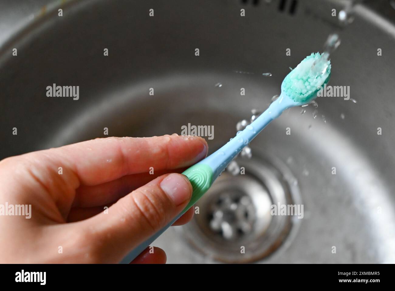 qualcuno sta lavando uno spazzolino da denti con un dentifricio Foto Stock