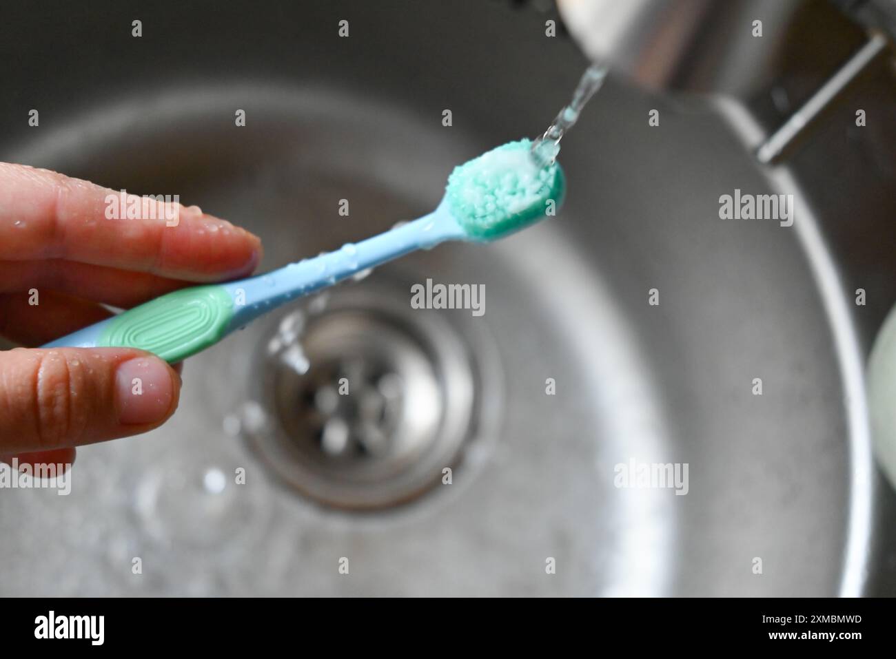 una persona ha in mano uno spazzolino da denti con un dentifricio Foto Stock